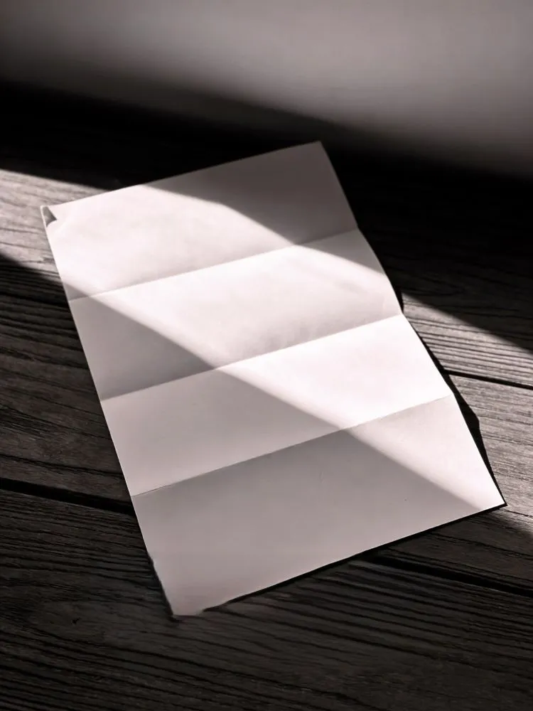 blank folded letter on a wooden table in soft sunlight after pet loss